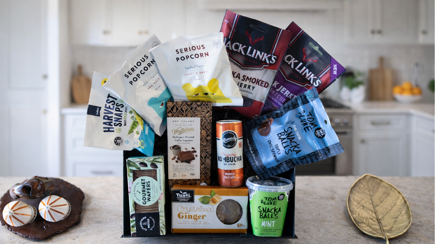 Assorted snacks and treats including popcorn, chips, and a cookie on a kitchen counter. Gift-DudeNibbles-ArchiesGiftBox