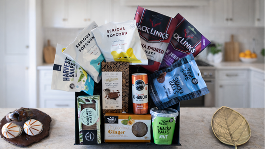 Assorted snacks and treats including popcorn, chips, and a cookie on a kitchen counter. Gift-DudeNibbles-ArchiesGiftBox