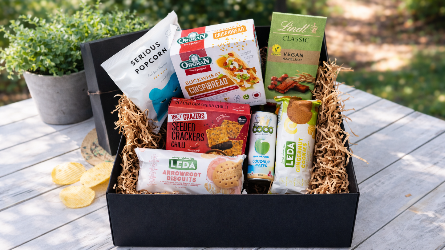 Snack box with various food items on a wooden table outdoors. Gifts-VeganCrunch-ArchiesGiftBox